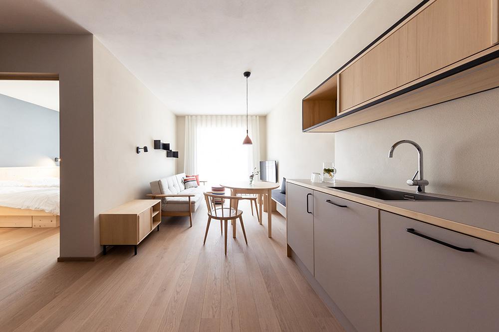 Helle Ferienwohnung Bozen mit Küche, Wohn-Essbereich und Blick ins Schlafzimmer