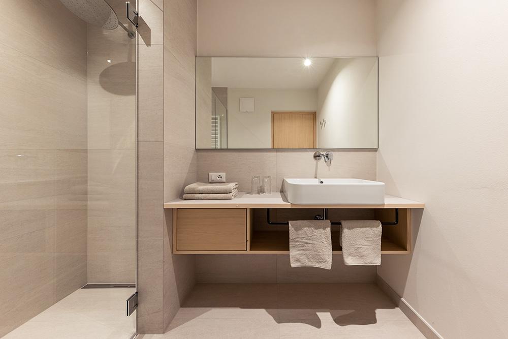 Modernes Badezimmer mit Regendusche und Holzwaschtisch in Ferienwohnung Lana