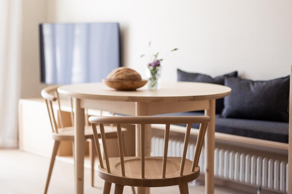 Runder Holzesstisch mit Stühlen und Sitzbank im Wohnbereich einer Ferienwohnung bei Meran